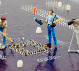 Circuit board with miniature construction workers and camera crew, Fraunhofer IZM