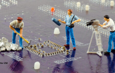 Circuit board with miniature construction workers and camera crew, Fraunhofer IZM