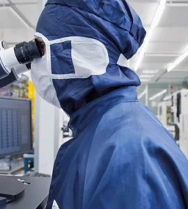 An employee in front of a microscope in the clean room (c) Fraunhofer IZM I Volker Mai