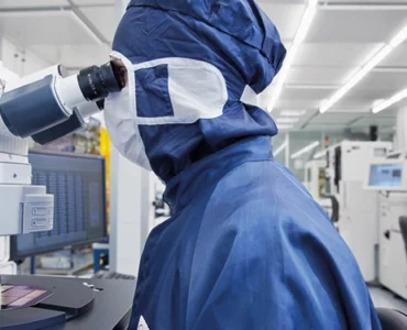 An employee in front of a microscope in the clean room (c) Fraunhofer IZM I Volker Mai